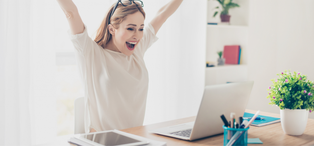 Woman cheering with arms raised in front of laptop