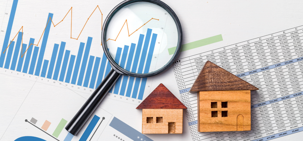 Magnifying glass and wood house cutouts on top of graphs and spreadsheet