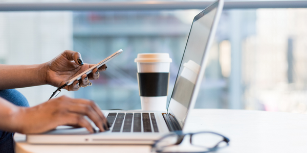 Student at desk with coffee, laptop and phone